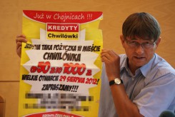 Wójt z plakatami, którymi oblepiono teren gminy. 