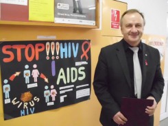 Dyrektor ZSP nr 2 Józef Kołak z czerwoną wstążeczką przy wystawie plakatów profilaktycznych.
